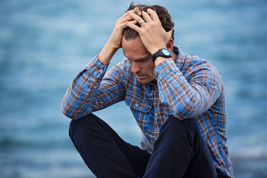 Distressed Man Holding Head in Despair by the Sea