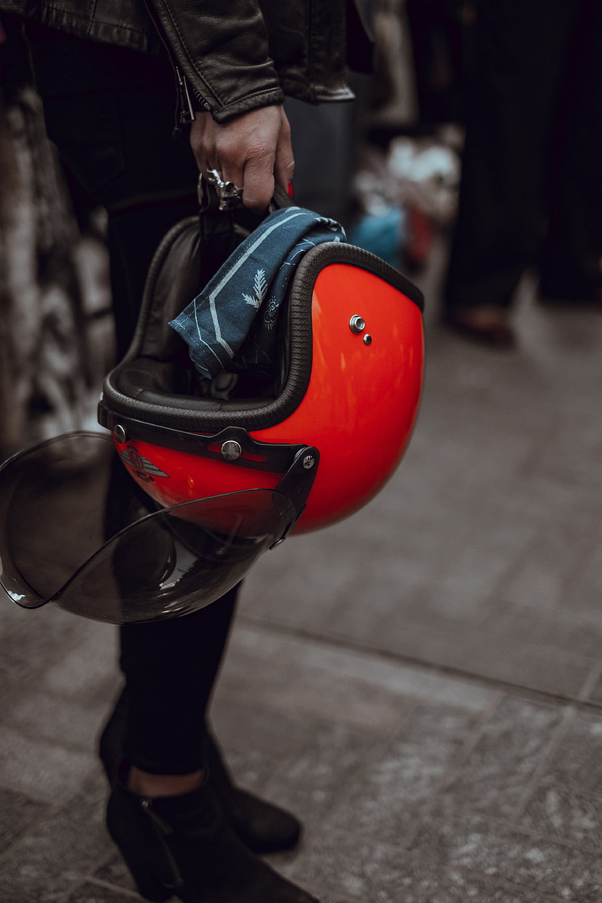Woman holding red motorcycle helmet with scarf