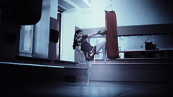 Female Kickboxer Kicking Heavy Bag in Gym