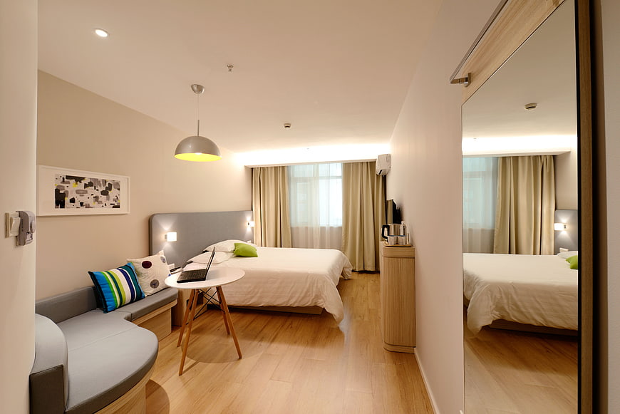Modern hotel room interior with bed, sofa, and mirror