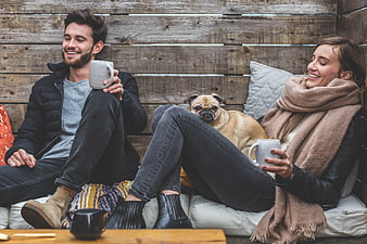 Happy couple drinking coffee with pug dog on patio