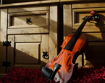 Violin Leaning Against Wooden Cabinet on Red Rug