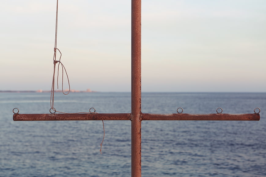 Rusty metal cross structure against calm sea background