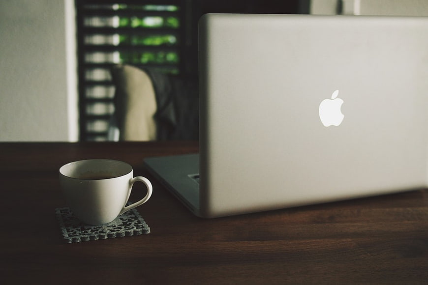Silver Laptop and Coffee Cup on Wooden Desk