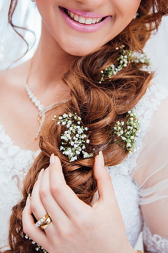 Close-up of bride's braided hair with baby's breath flowers and wedding rings