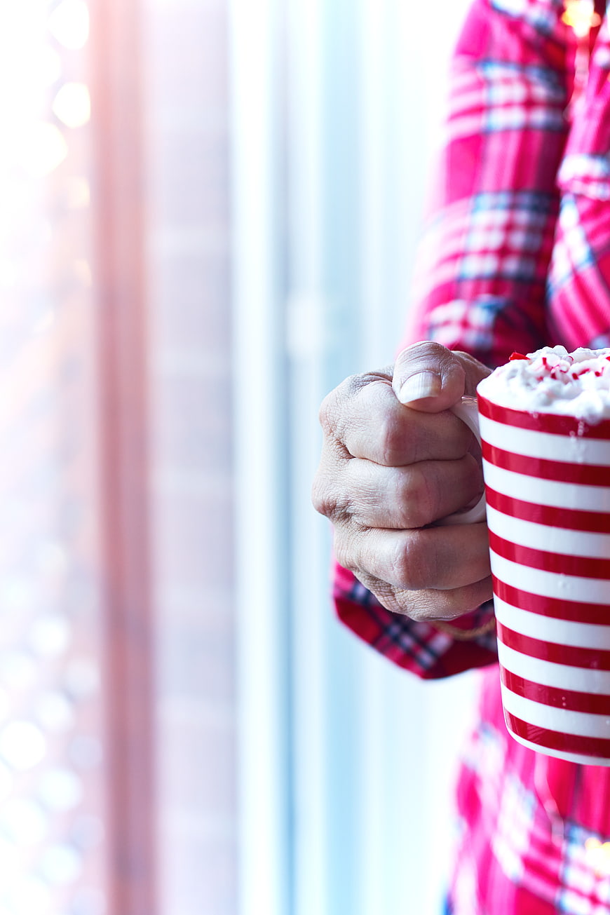 Woman holding festive red striped mug with whipped cream
