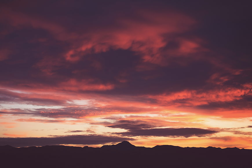 Dramatic purple and orange sunset sky over mountain silhouette