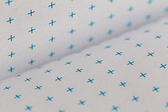 Close-up of white notebook pages with blue plus sign pattern