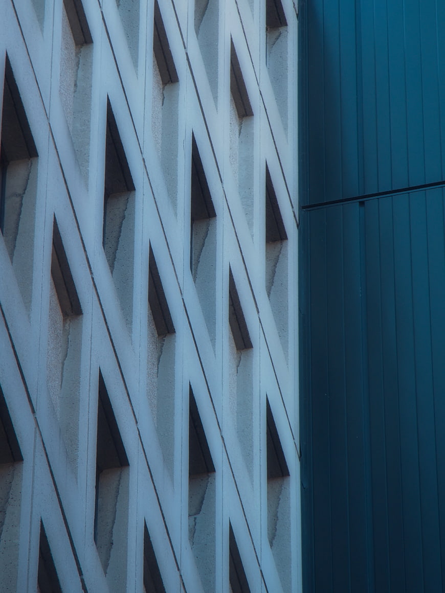 Modern building facade with geometric white lattice and blue panel