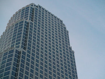 Low angle view of modern glass skyscraper against blue sky
