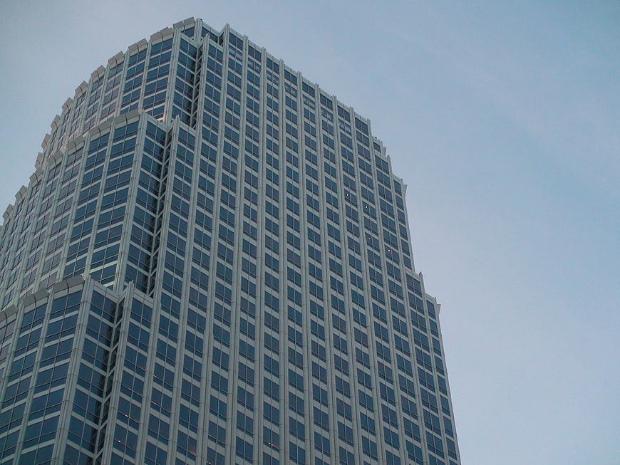 Low angle view of modern glass skyscraper against blue sky