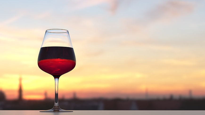 Glass of Red Wine Against Blurred Sunset Skyline