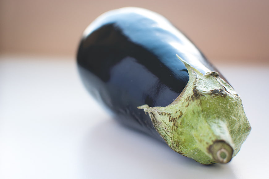 Close-up of a fresh purple eggplant on white background