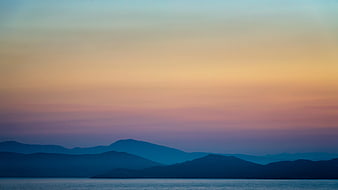 Serene Mountain Silhouette at Sunset Over Calm Water