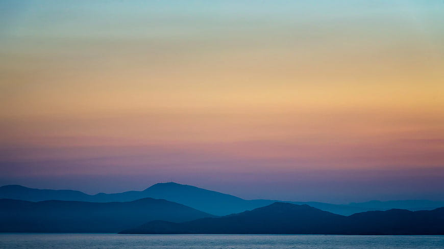 Serene Mountain Silhouette at Sunset Over Calm Water