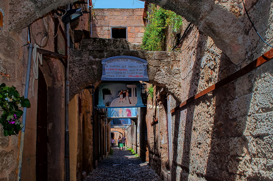 Narrow cobblestone alley in old town Rhodes with murals