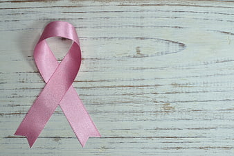 Pink breast cancer awareness ribbon on rustic white wood