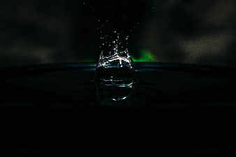 Dramatic water splash with green backlight on dark background