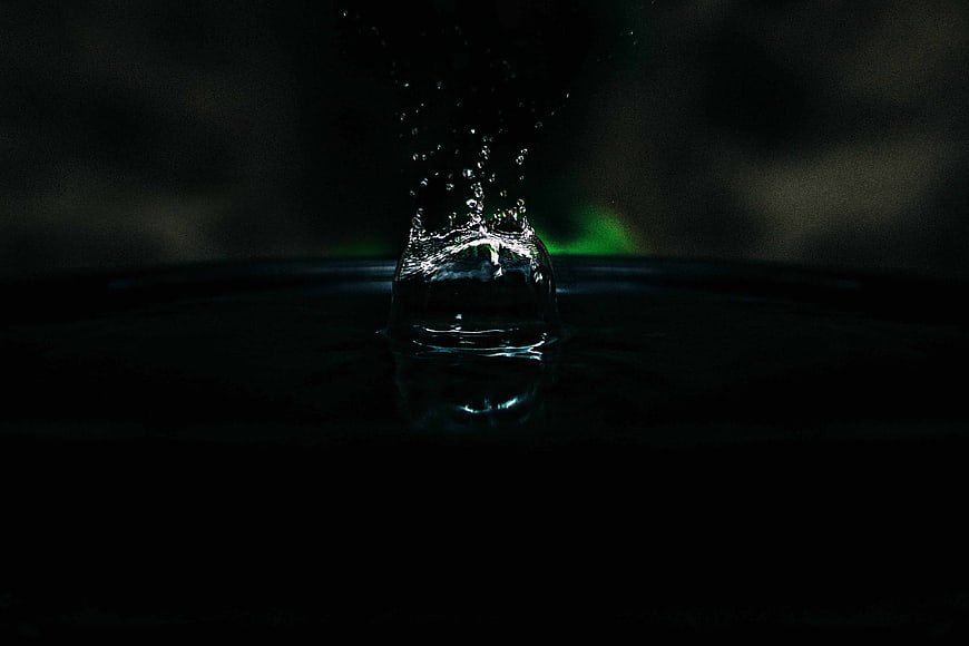 Dramatic water splash with green backlight on dark background