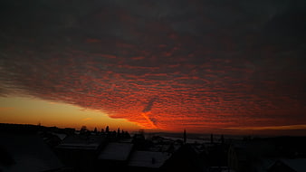 Dramatic fiery red sunset over snowy village rooftops