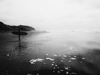 Silhouette of Surfer Walking on Black Sand Beach