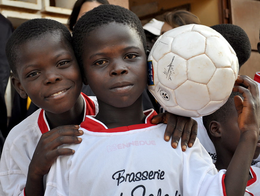 African Children Holding Soccer Ball In White Uniforms