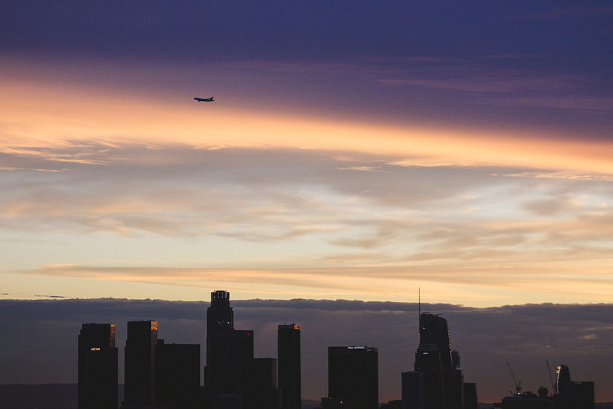 Silhouette of city skyline with airplane at sunset