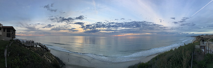 Panoramic Coastal Sunset View Over Calm Ocean And Sandy Beach