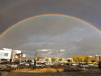 Vibrant Rainbow Arching Over Urban Parking Lot