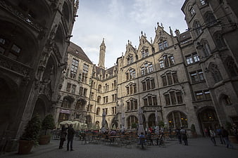 Historic Gothic courtyard with outdoor cafe seating and tourists