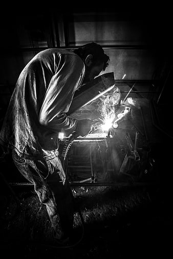 Black and white photo of a welder working in a dark workshop