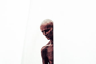 Bronze Sculpture of Emaciated Man Against White Background