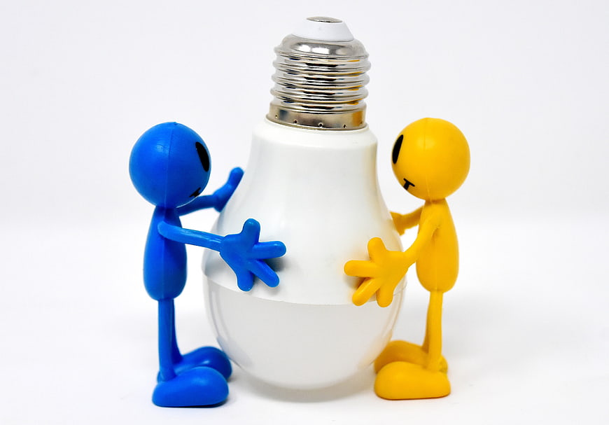 Blue and yellow figurines holding a white LED light bulb