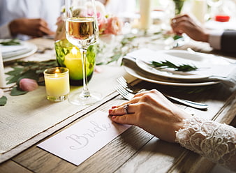 Bride's hand with ring on wedding place card at dinner table