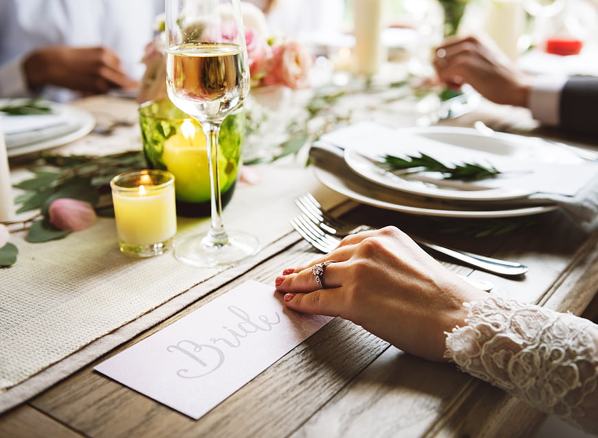 Bride's hand with ring on wedding place card at dinner table