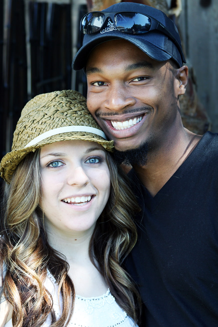 Happy interracial couple smiling outdoors in summer hats
