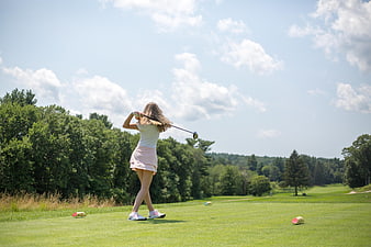 Woman Golfing on Green Course Under Blue Sky