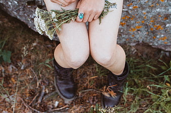 Woman holding wildflowers in forest with boots