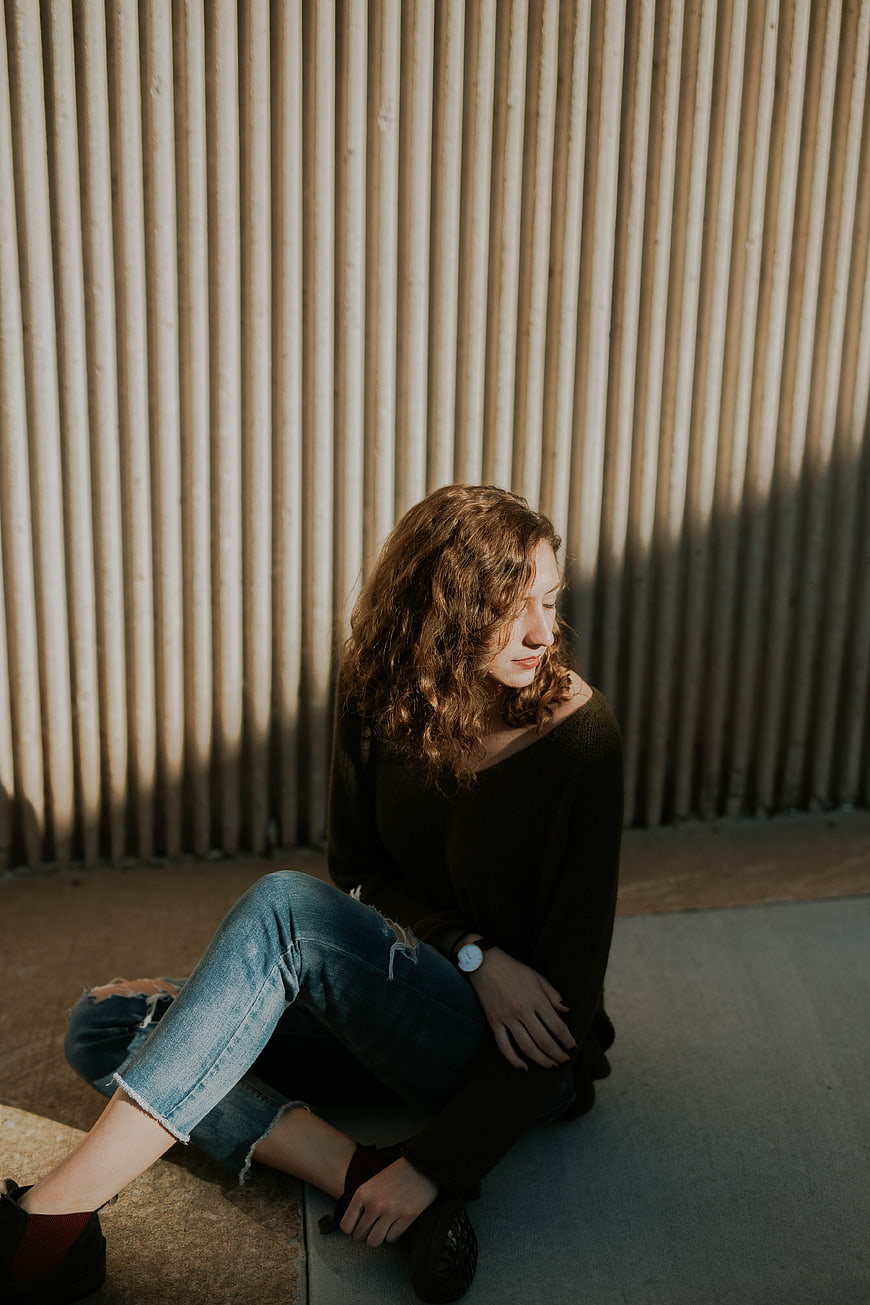 Woman sitting against corrugated wall in sunlight