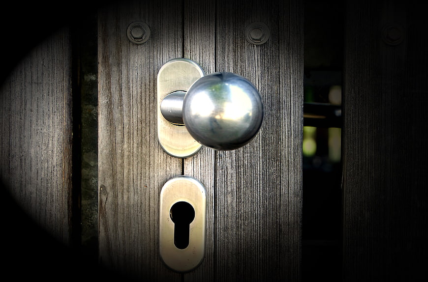 Close-up of silver door handle on weathered wooden door