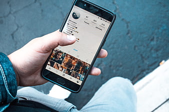 Hand holding smartphone displaying social media profile with blue background