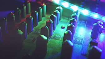 Close-up of audio mixer knobs with neon blue and green lighting