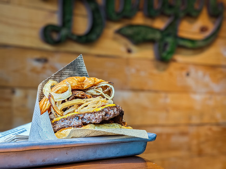 Gourmet cheeseburger with fried onions on a metal tray