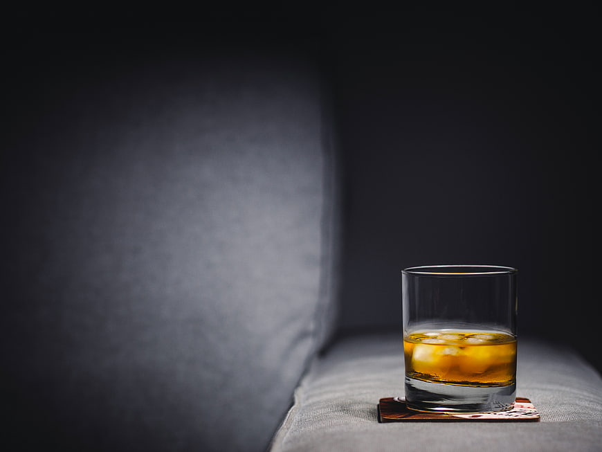 Glass of Whisky on Rocks on Grey Sofa