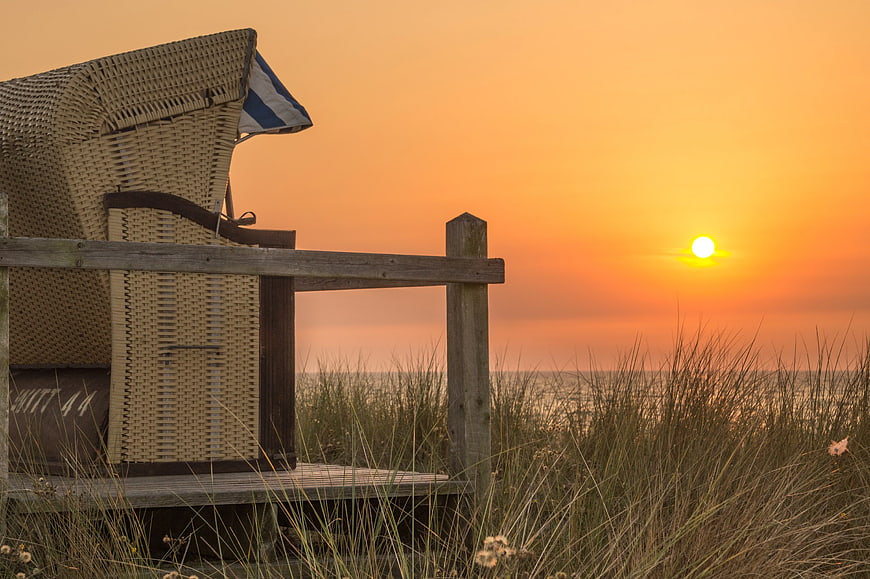 Traditional Wicker Beach Chair at Sunset Over Ocean