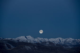 Full Moon Rising Over Snow-Capped Mountain Range at Night