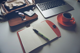 Flat lay workspace with laptop, coffee, notebook, and leather bag
