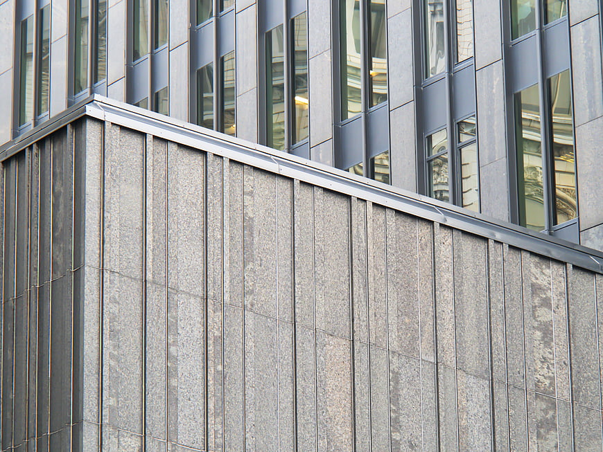 Modern gray stone building facade with glass windows
