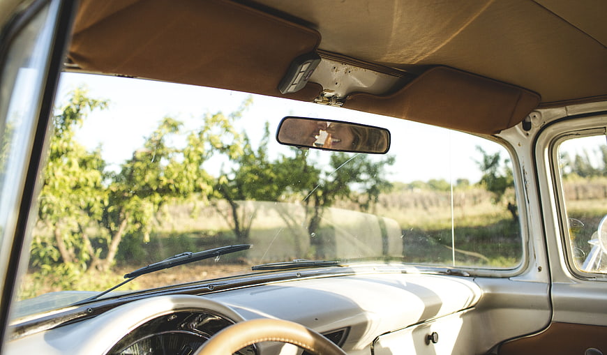 Vintage car interior view with smiling woman in rearview mirror