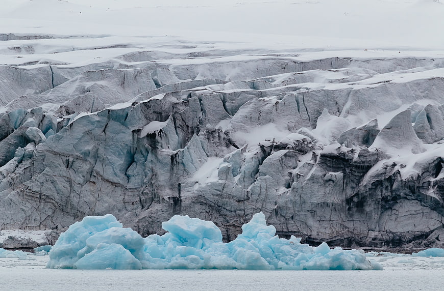Massive Glacier Face with Blue Iceberg in Foreground